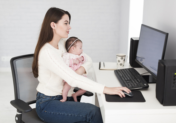 Mulher com bebê no colo trabalhando em home office